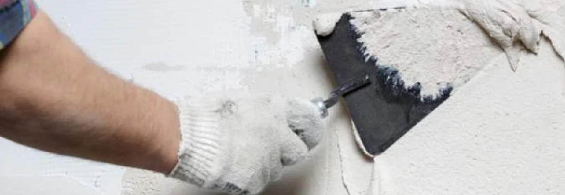 Person trägt Putz mit Spachtel auf